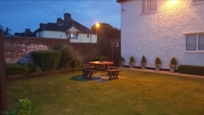 A backyard with a wooden table and chairs, surrounded by a low brick wall and a white fence. - The Balkan Lodge Oxford  (Oxford)