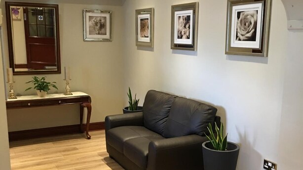 A modern living room with a dark leather sofa, wooden flooring, and framed artwork on the walls. - The Balkan Lodge Oxford  (Oxford)