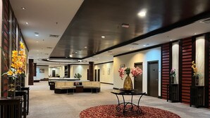 A hotel lobby with a reception desk, seating area, and a red carpeted circle. - Tanjong Puteri Golf Resort - Malaysia (Pasir Gudang)