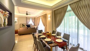 A dining area with a table set for four, a sofa in the background, and a large window with curtains. - Tanjong Puteri Golf Resort - Malaysia (Pasir Gudang)