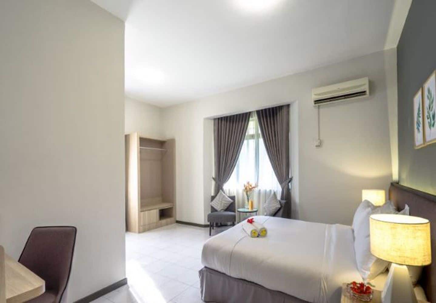 A hotel room with a bed, bedside table, lamp, and a view of a balcony.