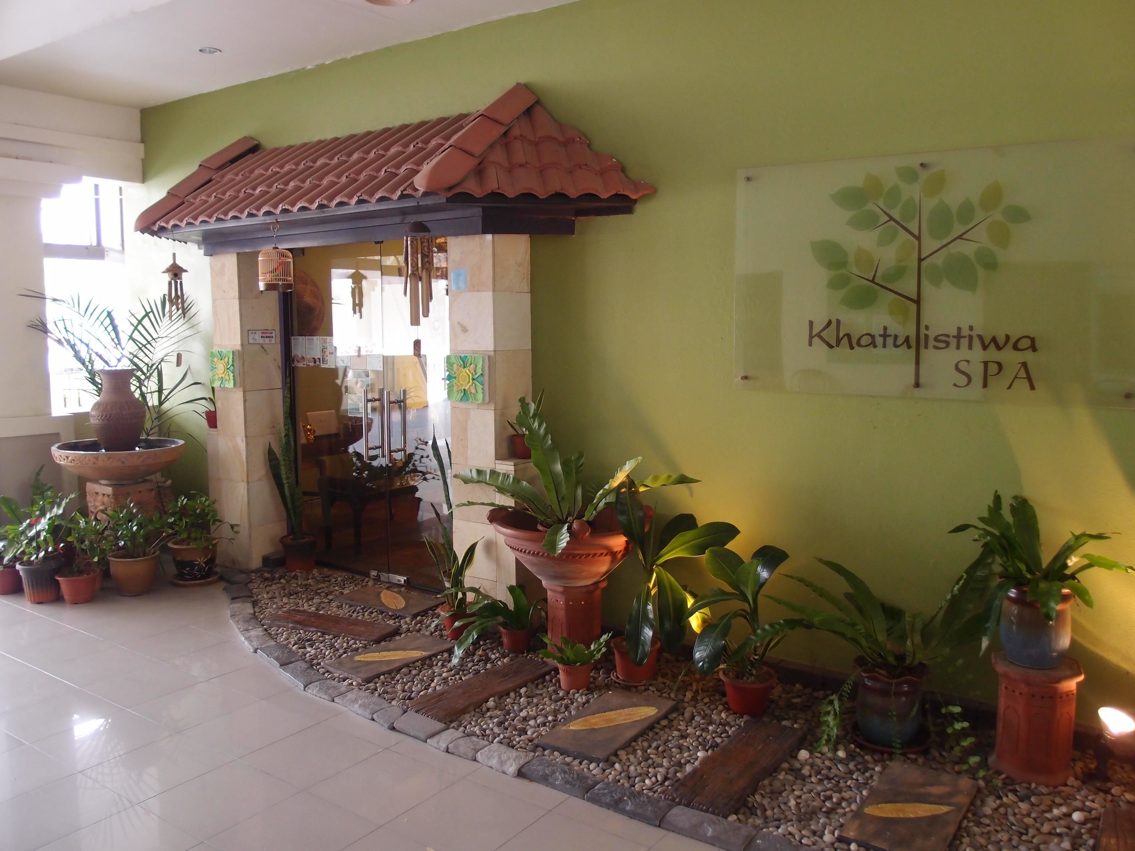 A spa entrance with a tiled roof, potted plants, and a sign reading "Khatuistiwa SPA".