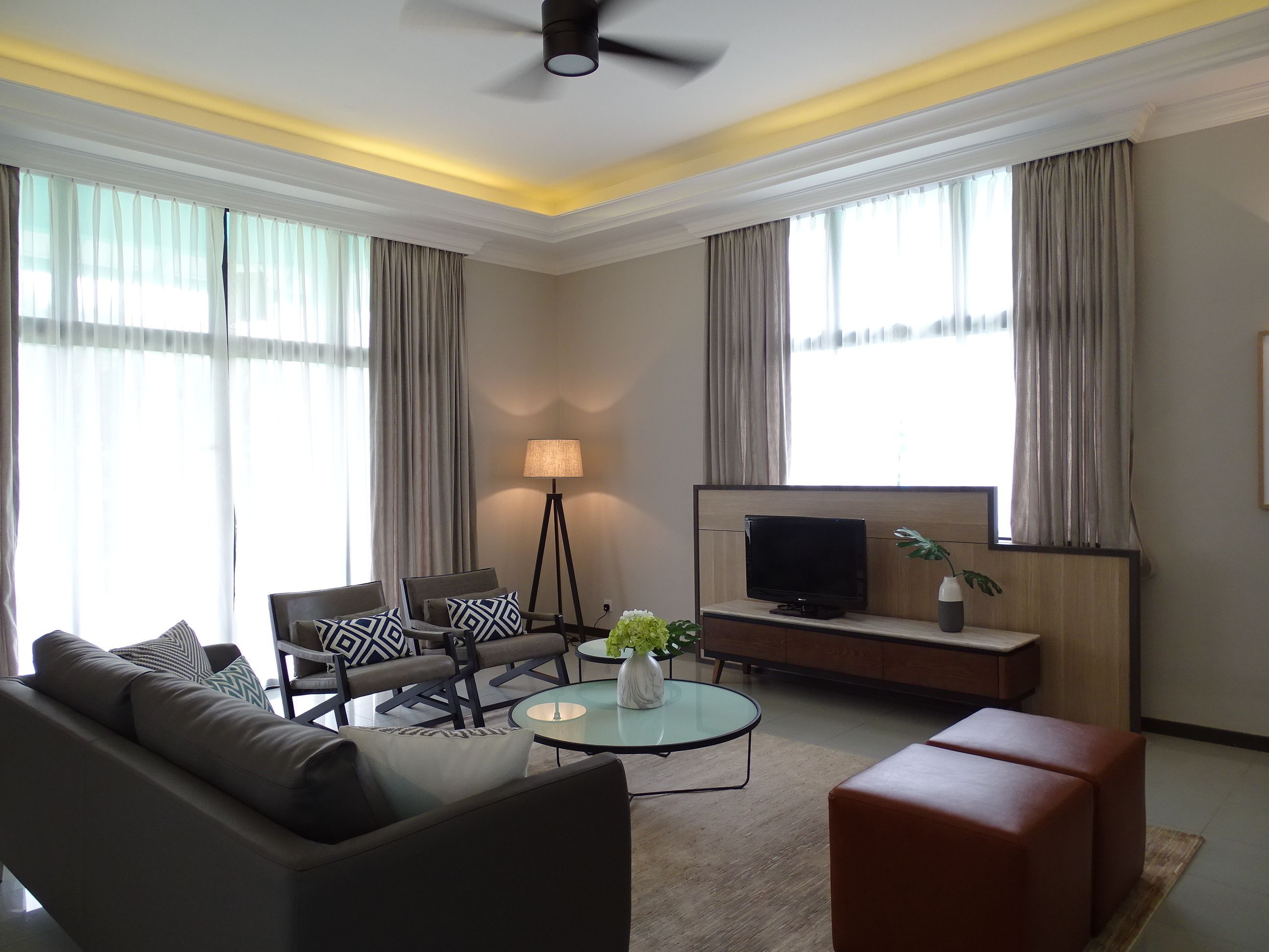 A modern living room with a sofa, armchairs, a coffee table, a TV, and a floor lamp.