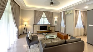 A modern living room with a sofa, coffee table, and a TV on a wooden cabinet. - Tanjong Puteri Golf Resort - Malaysia (Pasir Gudang)