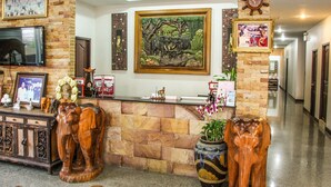 Una zona de recepció amb paret de pedra, escultures de fílberts de fusta, un quadre gran emmarcat i un televisor fixat a la paret.