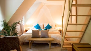 Een slaapkamer met een bed, een nachtkastje, een stoel, een ladder en een potplant.