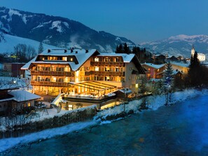 A multi-story hotel with balconies, a covered outdoor area, and a view of snow-covered mountains. - Hotel Kaprunerhof (Kaprun)