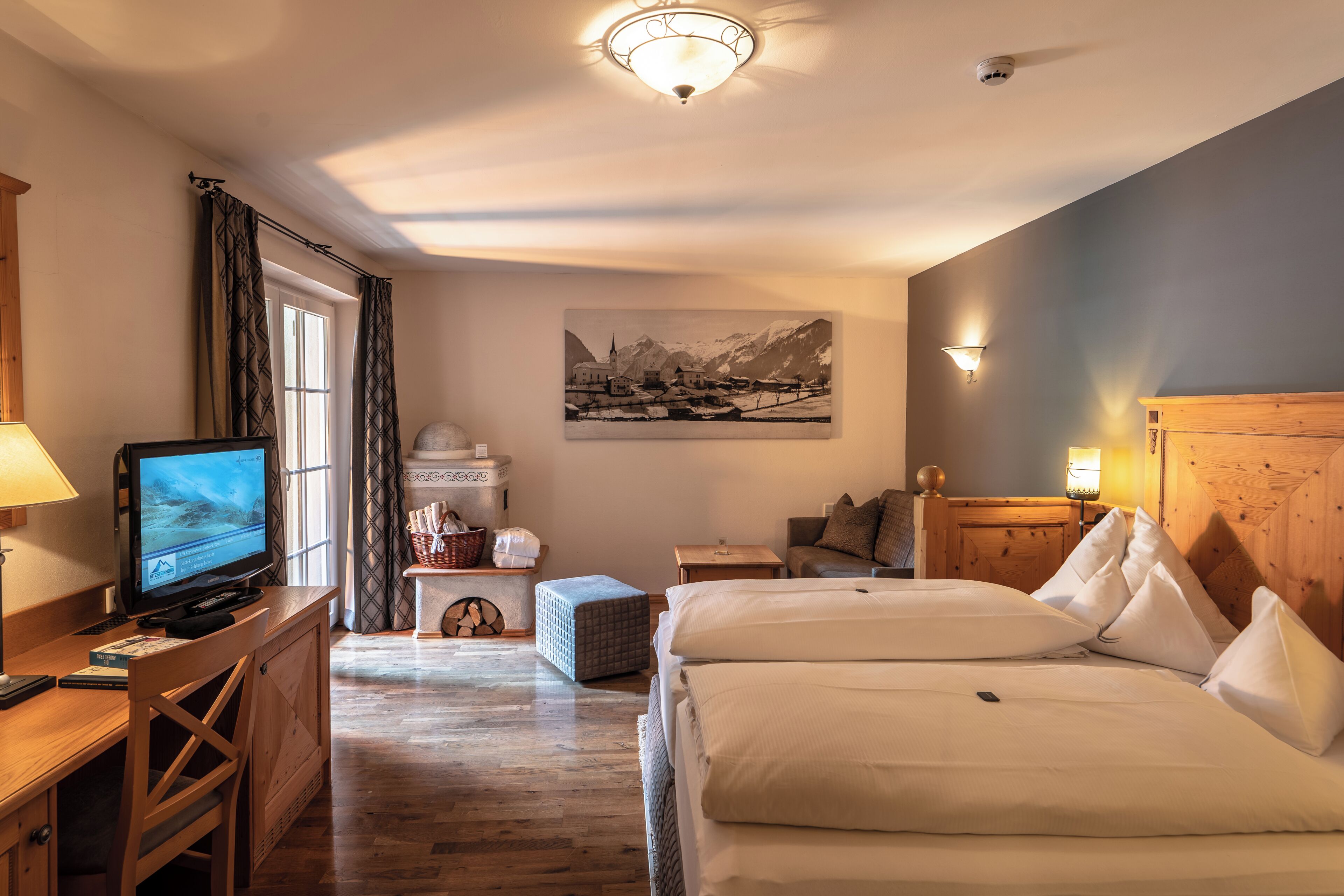 Ein Hotelzimmer mit einem Bett, einem Schreibtisch mit Computer, einem Fernseher, einem Kamin und einem Bild an der Wand.