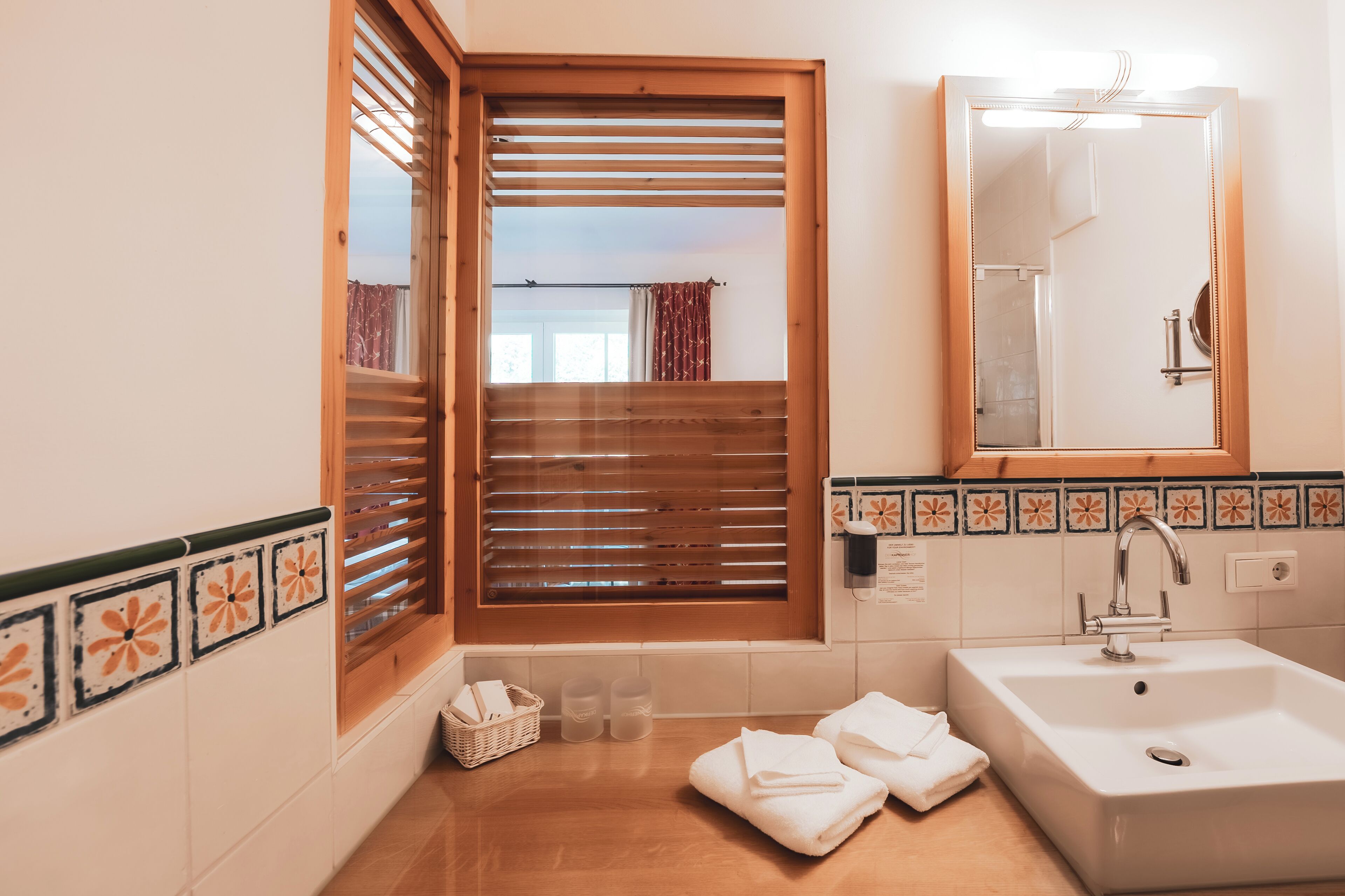 A bathroom with a wooden window, a sink, and a mirror.