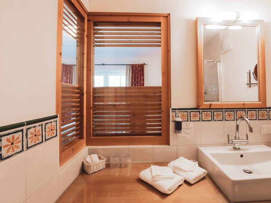 A bathroom with a wooden window, a sink, and a mirror.
