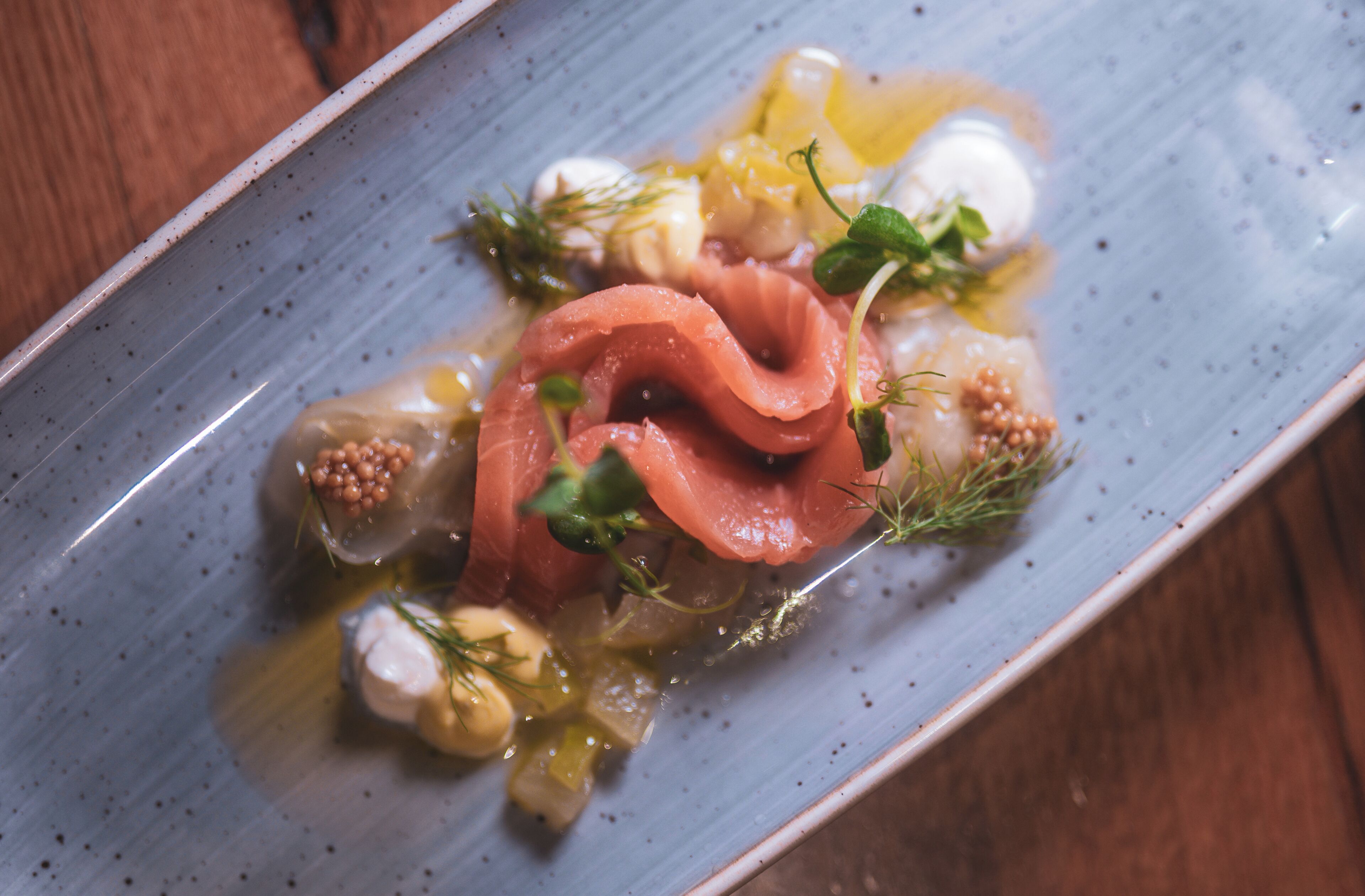 Une assiette de nourriture comprenant du saumon, des légumes et une sauce.