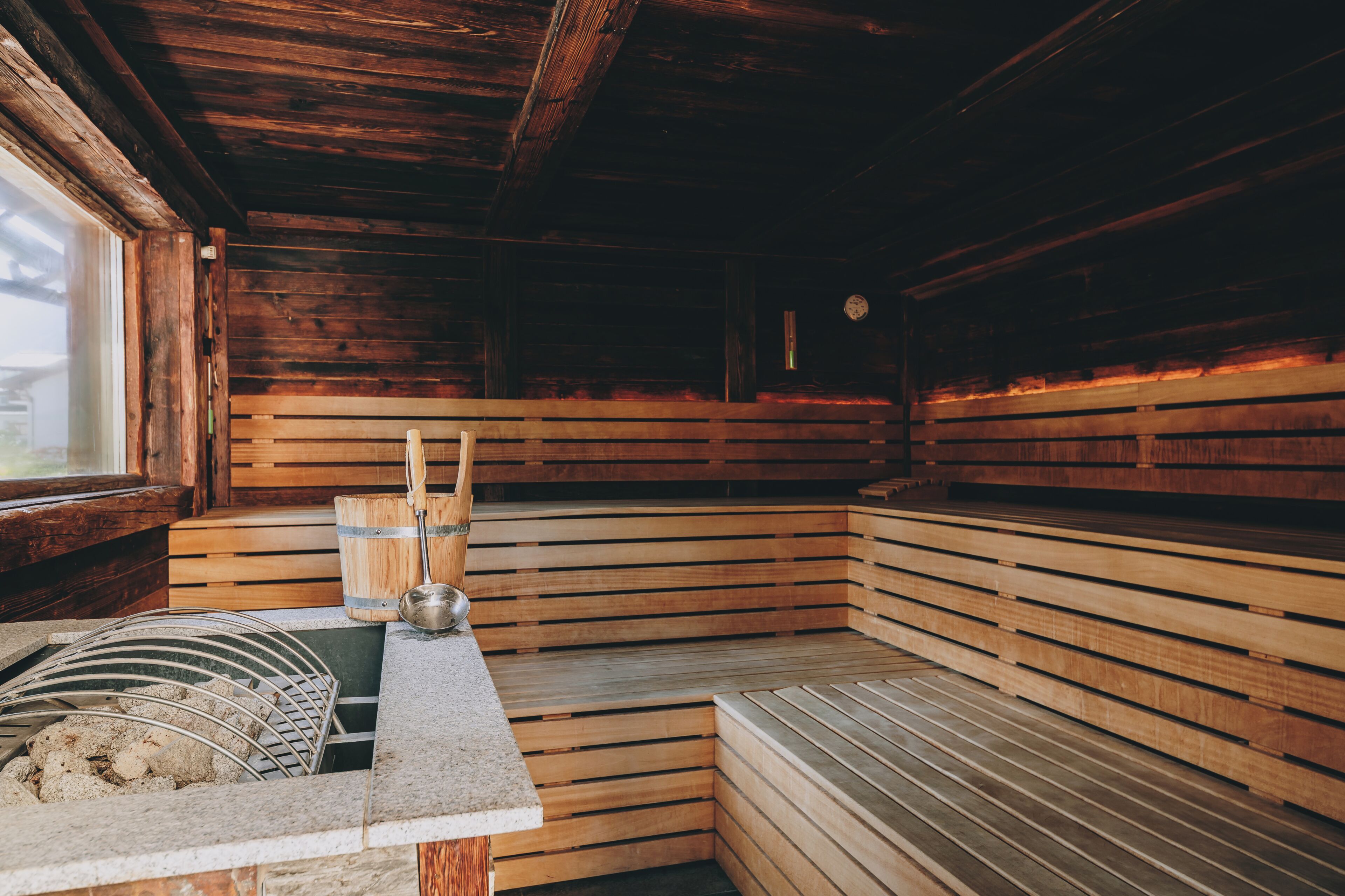 A sauna with wooden benches, a metal bench, and a stone bench.