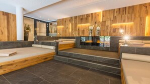 A modern spa room with wooden paneling, a fireplace, and multiple seating areas. - Hotel Kaprunerhof (Kaprun)