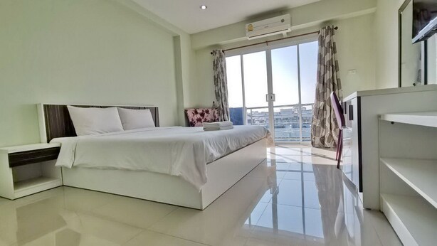 A modern bedroom with a large bed, a TV, and a balcony with curtains.