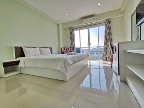 A modern bedroom with a large bed, a TV, and a balcony with curtains.