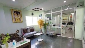 A reception area with a sofa, a chair, a desk with a computer, and a plant.