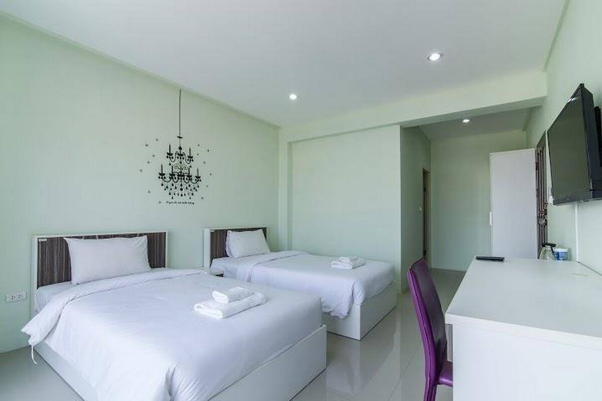 A hotel room with two beds, a desk, and a TV.