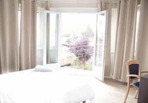 Een hotelkamer met een bed, een stoel en uitzicht door een geopende deur.