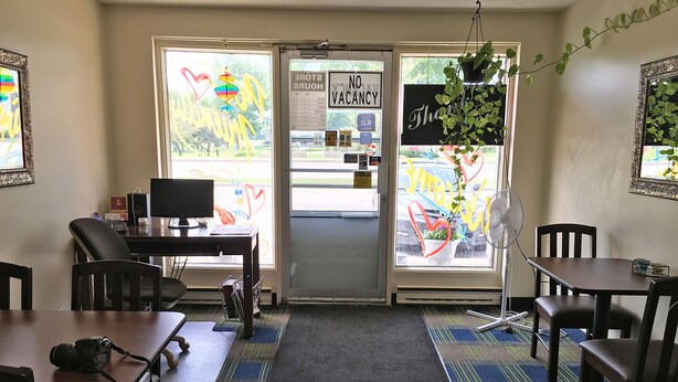 A room with a desk, computer, chairs, and a door with a 'No Vacancy' sign. - Westgate Inn (Portage La Prairie)