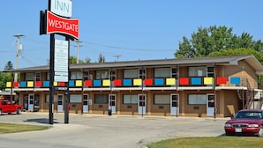 A motel with a sign indicating it is the 'INN WESTGATE' with amenities like big screen TVs, free continental breakfast, free WiFi, and a business center. - Westgate Inn (Portage La Prairie)