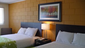 A hotel room with two beds, a nightstand with a lamp, and a framed picture on the wall. - Westgate Inn (Portage La Prairie)