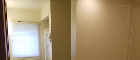 A bathroom with wooden paneling, a white sink, and a window with blinds.