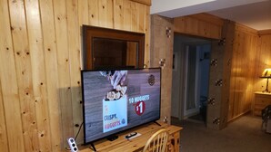 A wooden desk with a television displaying a Burger King advertisement, a chair, and a wooden cabinet. - The Willard Munger Inn (Duluth)