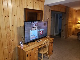 Un escritorio de madera con un televisor mostrando un anuncio de Burger King, una silla y un armario de madera.