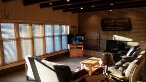 A cozy living room with wooden furniture, a television, and a sign reading "Willard Hunger State Trail." - The Willard Munger Inn (Duluth)