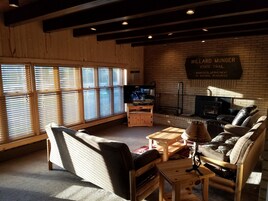 Una sala de estar acogedora con muebles de madera, un televisor y un cartel que dice 'Willard Hunger State Trail'.