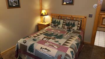 Un dormitorio con cama de madera, una mesita de noche con lámpara y dos cuadros en la pared.