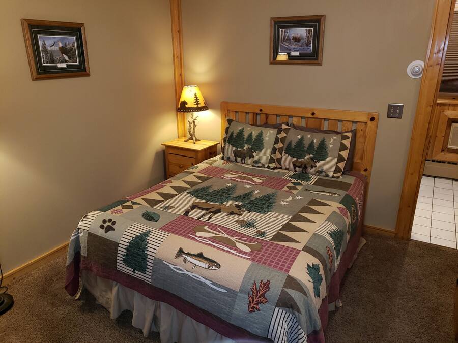 Un dormitorio con cama de madera, una mesita de noche con lámpara y dos cuadros en la pared.