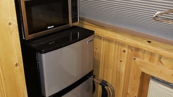 A compact kitchen with a stainless steel refrigerator, a microwave, and a coffee maker on the countertop.