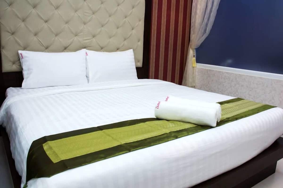 A neatly made bed with white linens and a green and white striped blanket.