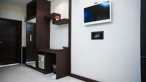 A modern hallway with a dark wooden structure, a flat-screen TV mounted on the wall, and a small shelf with decorative items. - Roses Hua Hin Hotel (Hua Hin)