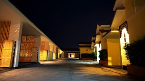 A hotel corridor with multiple doors, some with wooden shutters, and a few with illuminated signs. - Roses Hua Hin Hotel (Hua Hin)