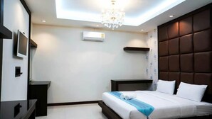 A modern hotel room with a bed, a TV, a ceiling light, and an air conditioning unit. - Roses Hua Hin Hotel (Hua Hin)