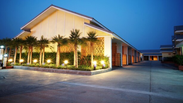 A modern hotel with a flat roof, a covered walkway, and palm trees. - Roses Hua Hin Hotel (Hua Hin)