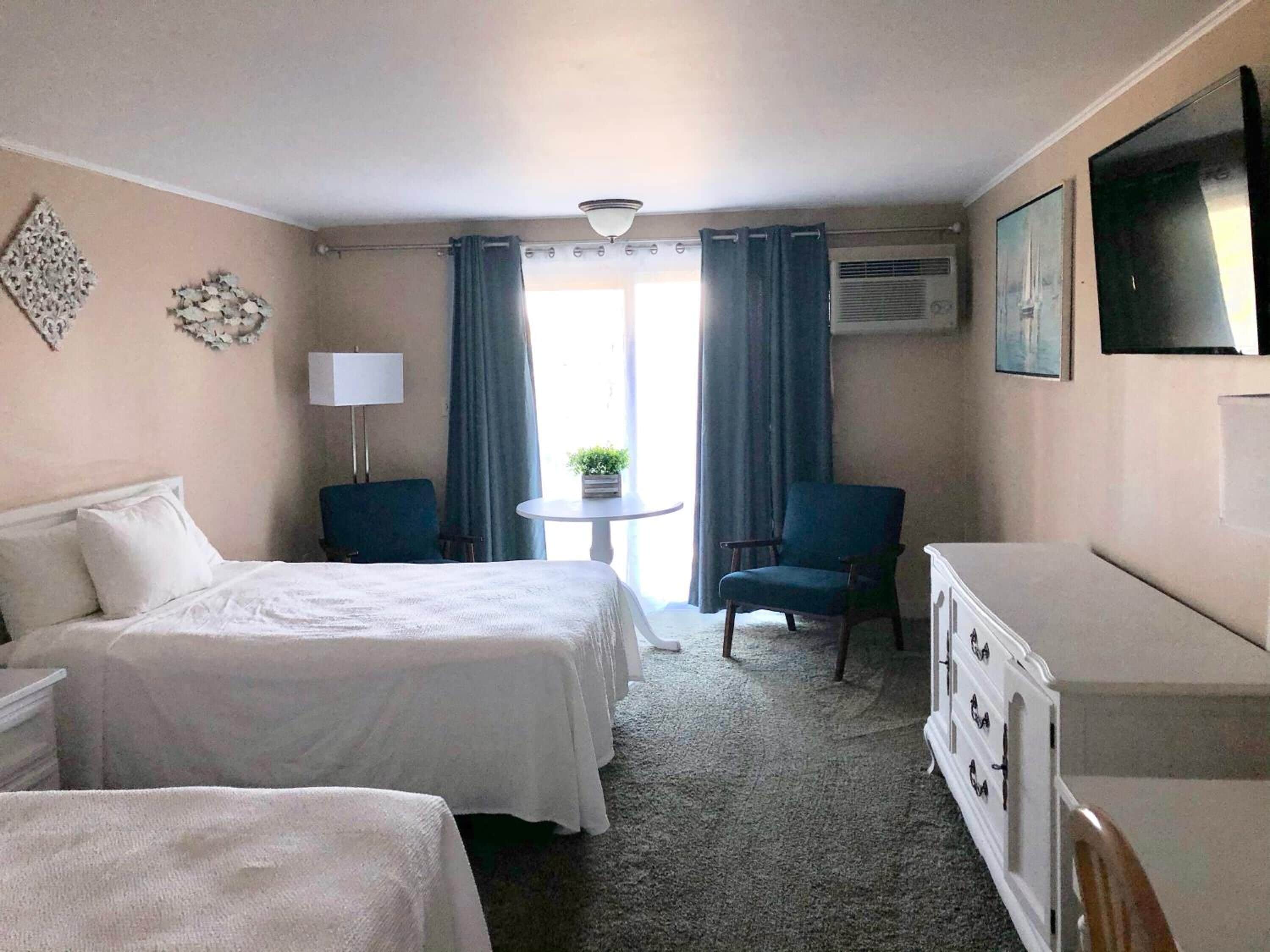 A hotel room with two beds, a desk, a chair, and a dresser.