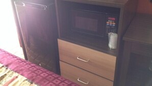 A compact kitchenette with a microwave, a small refrigerator, and a cabinet with drawers. - Budget Inn (Tonawanda)