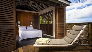 A wooden deck with a bed and a lounge chair. - Hôtel Plein Soleil (Le Francois)