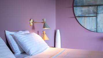 Une chambre à coucher avec un lit, des oreillers, une lampe fixée au mur et une fenêtre donnant sur un beau paysage.