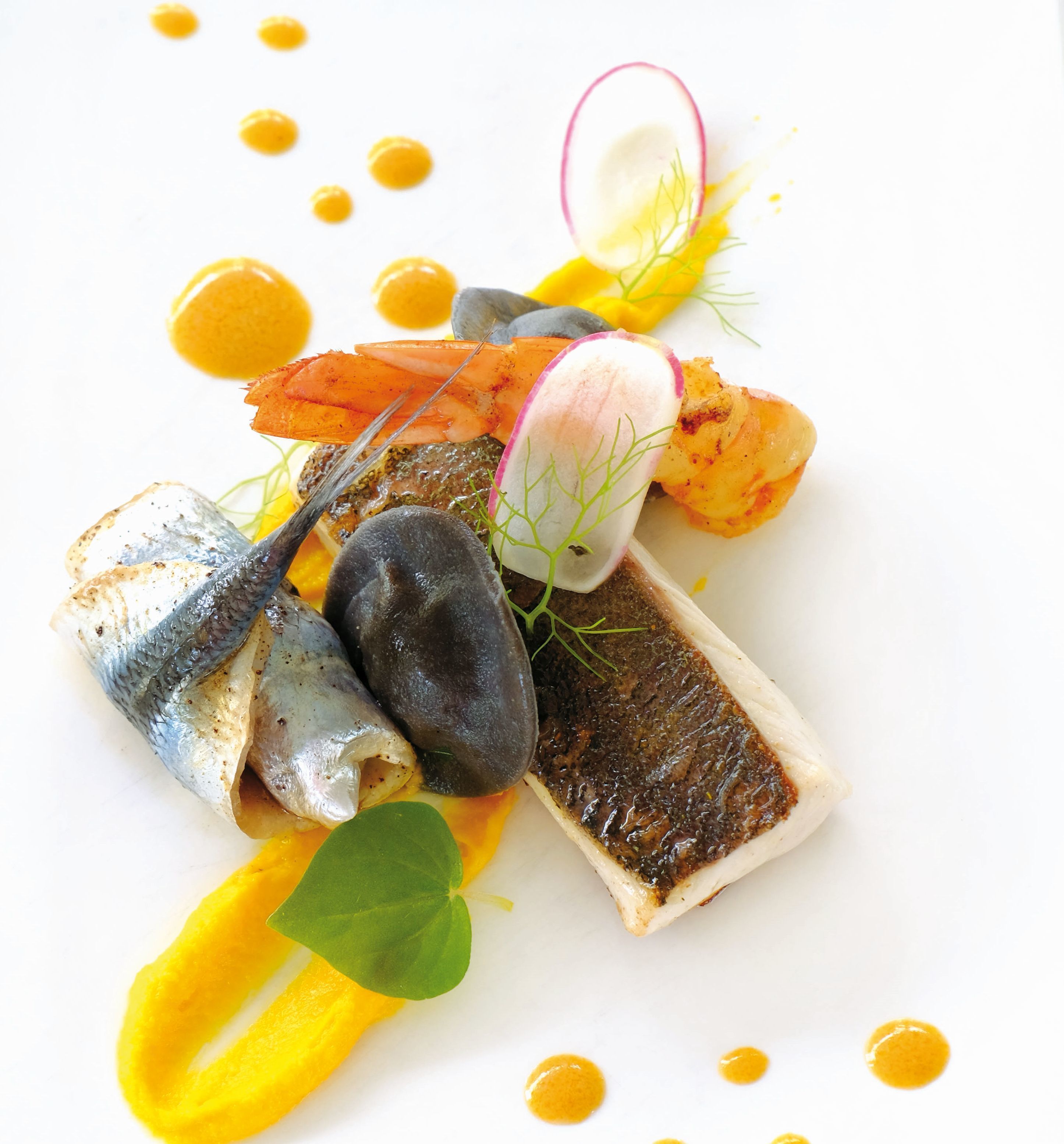 A dish with fish, shrimp, and vegetables on a white plate.