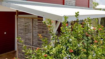 A two-story house with a covered patio, a garage, and a garden with flowering plants.