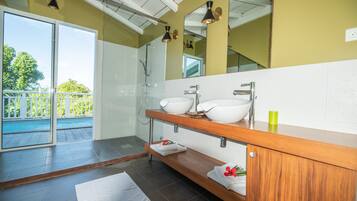 A modern bathroom with a large mirror, two sinks, and a shower.