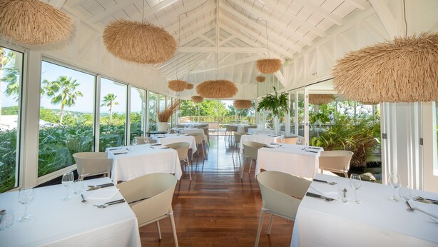 A restaurant with white tables and chairs, large windows, and hanging rattan lamps. - Hôtel Plein Soleil (Le Francois)