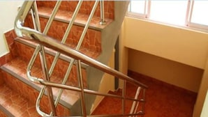Una escalera con barandillas de metal y escalones de baldosas rojas.