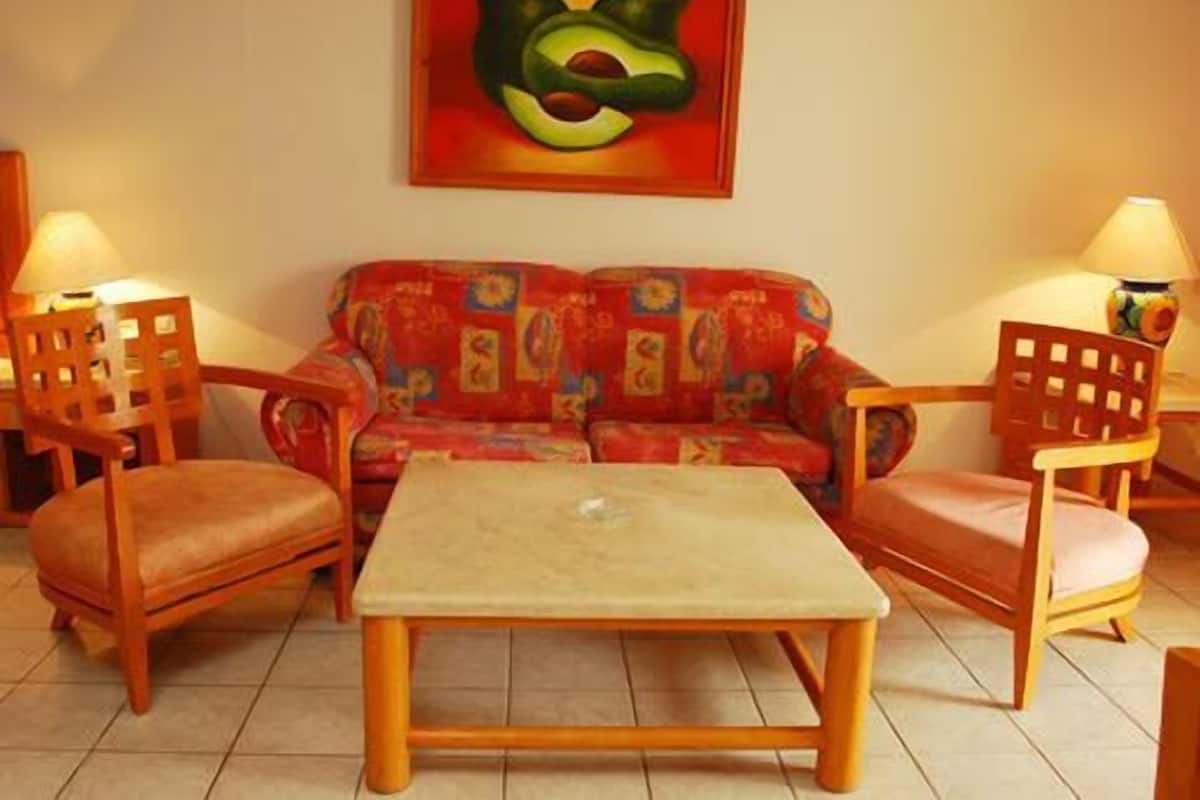 Un salon avec un canapé, deux fauteuils, une table basse et un tableau accroché au mur.