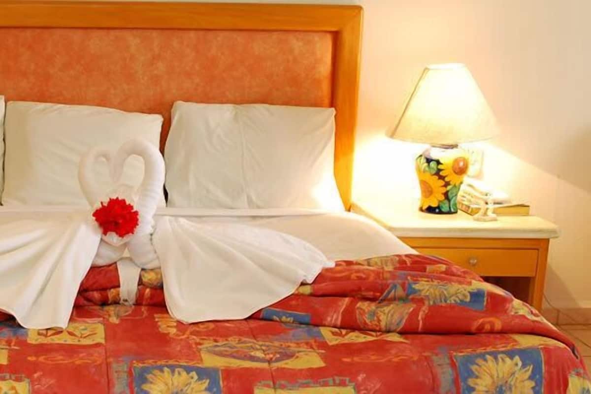 Une chambre d’hôtel avec un lit, deux tables de chevet et des lampes.