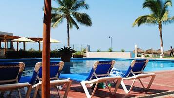 A poolside area with lounge chairs and a view of the ocean.